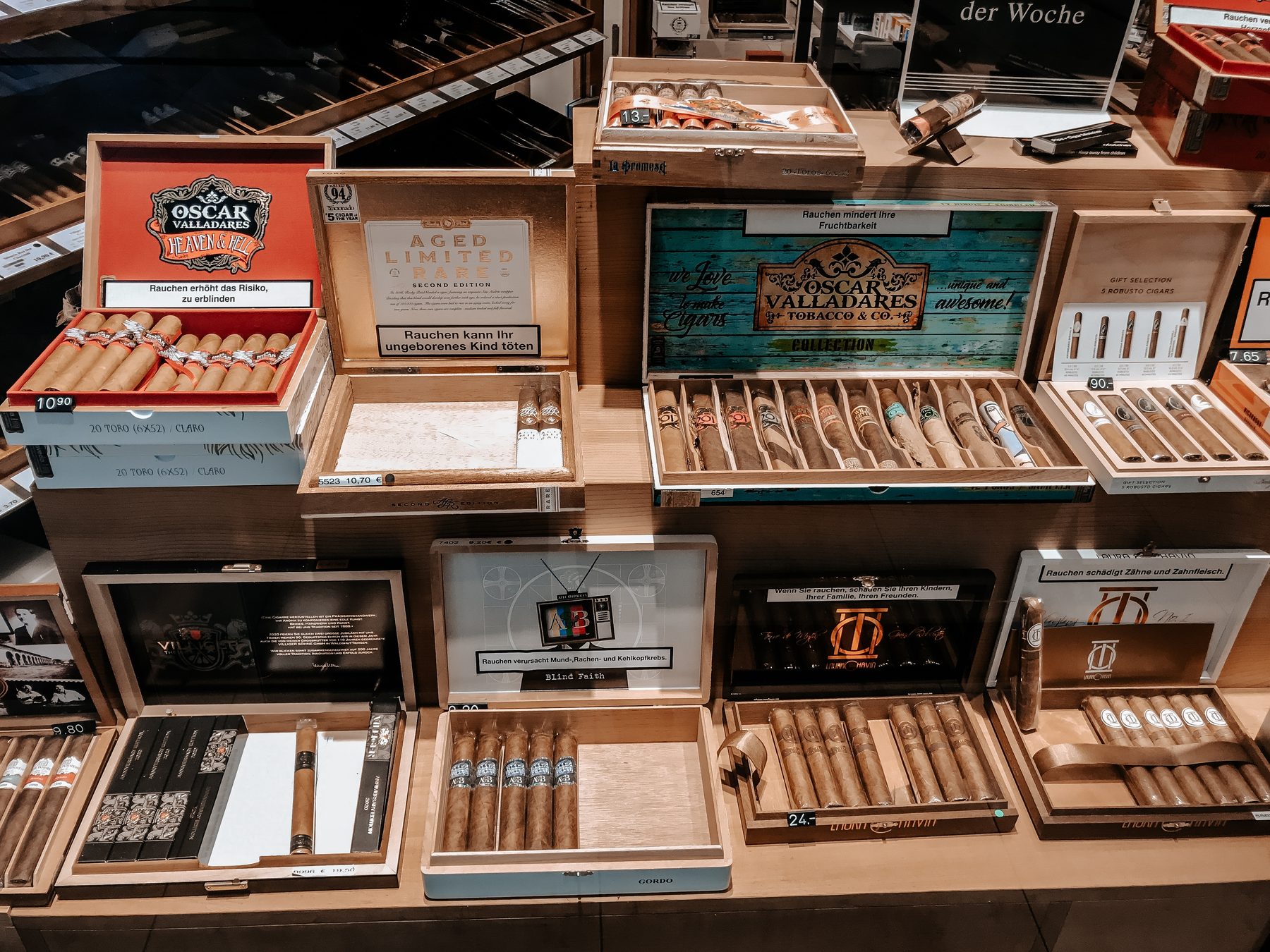 Open cigar boxes arranged on a tobacconist's shelf with price tags on each box