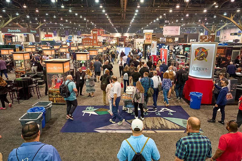 Crowded PCA trade show floor with brand booths, banners, and streams of retailer attendees